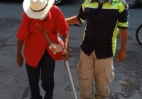 Crónica urbanaBombero con uniforme de La Ruta Correctaayuda a un anciano a cruzar la calle