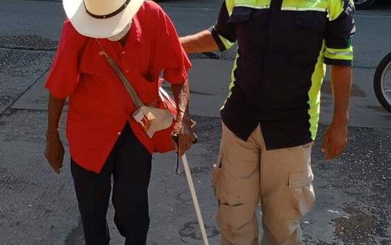 Crónica urbanaBombero con uniforme de La Ruta Correctaayuda a un anciano a cruzar la calle