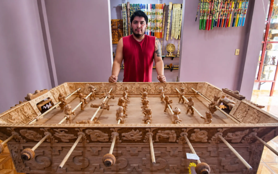 Artesano mexicano está tallando una mesa de futbolito de madera que representa a dioses mayas y aztecas